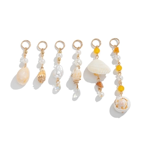 Macro detail of six ocean-themed pendants featuring pearls and natural seashells