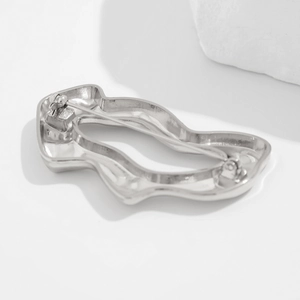 Détail d'une broche argentée en métal liquide au motif froissé avec fermeture sécurisée