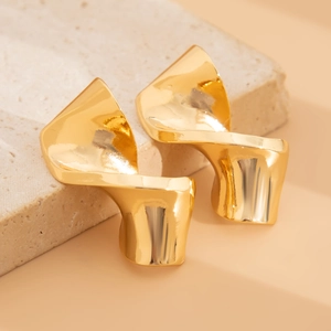Detail shot of golden twisted teardrop earrings with a glossy hammered metal finish