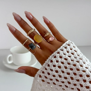 Detailed view of six vintage gold alloy rings set with amber and pink gemstones on hand