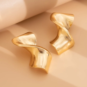 Close-up of golden irregular twisted drop earrings with polished metallic surface