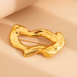 Détail d'une broche dorée irrégulière avec texture métallique effet lave en fusion
