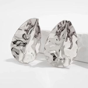 Macro shot of silver drop earrings with a modern hammered texture and irregular fold design