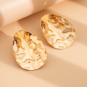 Detail view of irregular hammered gold teardrop earrings with artistic wrinkled texture