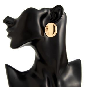 Close-up of golden polished round stud earrings on a black mannequin model