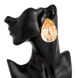 Macro detail of irregular hammered water drop earring in gold finish on female model