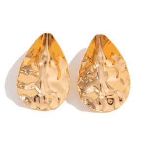 Detailed close-up of golden teardrop earrings featuring irregular hammered metal texture