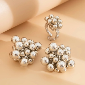 Macro detail of geometric silver bead cluster ring and earrings with mirror finish