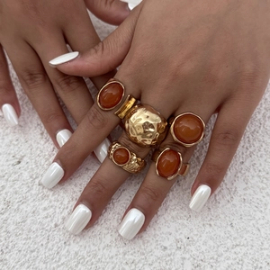 Close-up of bohemian gold rings set with amber gemstones and hammered metal texture