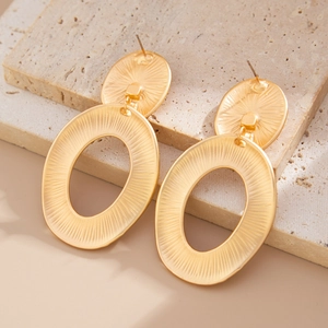 Detail of matte gold geometric drop earrings with vertical ribbed texture on stone