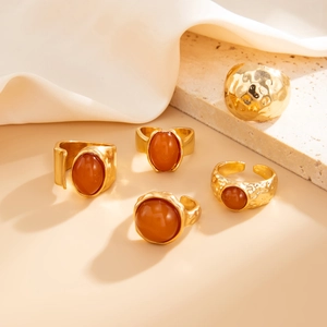 Detail of vintage gold rings set featuring red-brown resin gems on stone background