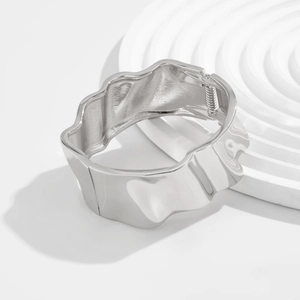 Detail view of silver wave texture wide bangle with spring hinge design on white stand