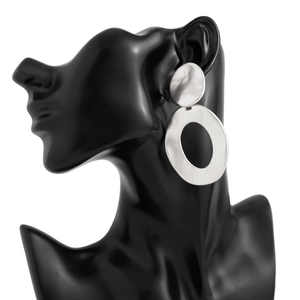 Detail view of large silver geometric drop earrings on a professional black model display