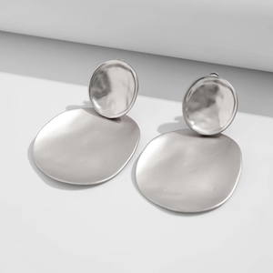 Detail of silver geometric earrings with hand-hammered texture and irregular round pendants