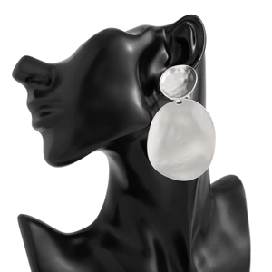 Detail of large silver geometric drop earrings with hammered texture on black display
