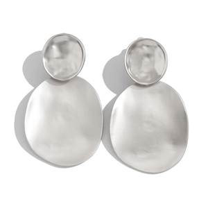 Macro detail of irregular geometric silver drop earrings with hammered metal texture