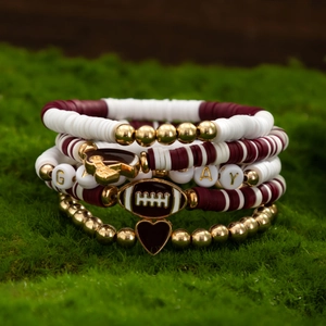 Close-up of 5-piece burgundy and gold football themed beaded bracelet set on moss