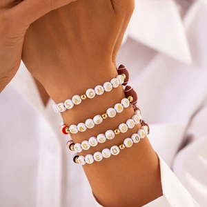 Close-up of four stacked beaded bracelets with Super Bowl football themed letter beads