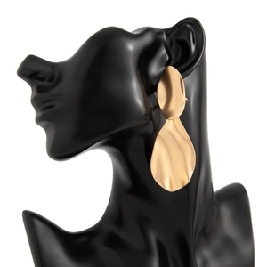 Macro detail of gold abstract drop earrings featuring irregular hammered geometric textures