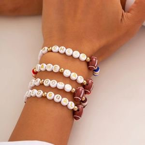 Close-up of four layered American football beaded bracelets with sports letter charms