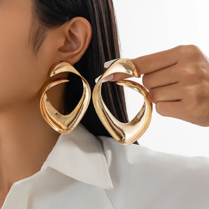 Close-up of oversized golden irregular spiral earrings with high-polish metallic finish
