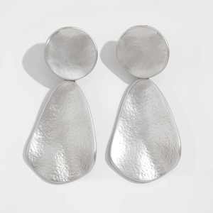 Detail of silver drop earrings with hammered finish and irregular geometric shapes