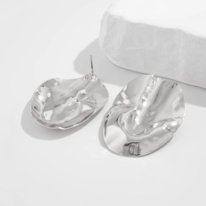 Macro shot of silver chunky irregular oval stud earrings with crinkled metal texture
