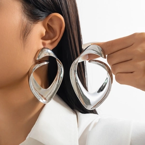 Macro shot of large polished silver bow earrings with a fluid sculptural wave design