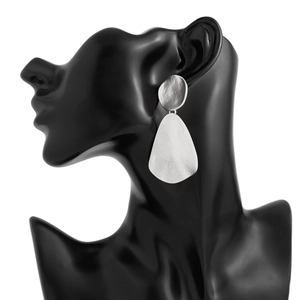 Macro detail of silver teardrop earrings featuring a unique hammered metal texture