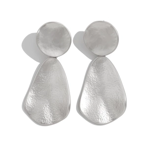 Silver hammered metal earrings featuring irregular teardrop pendants on white background