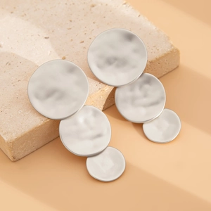 Macro detail of matte silver earrings with triple hammered geometric discs on stone
