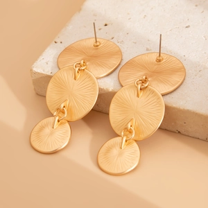 Detailed macro view of tiered gold disk earrings with radiant sunburst texture on stone