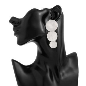 Macro detail of geometric silver layered circular earrings on a black display model