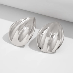 Detail of silver waterdrop earrings with vertical texture on geometric white stands