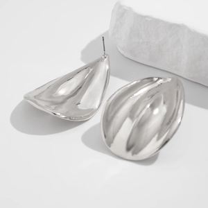 Close-up of irregular water drop earrings with a metallic hammered texture in silver