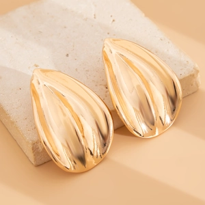 Detailed close-up of golden leaf earrings with rippled texture on stone display