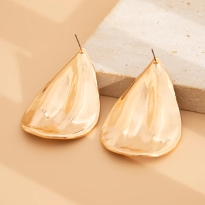Detail of large gold teardrop earrings with hammered texture on stone display