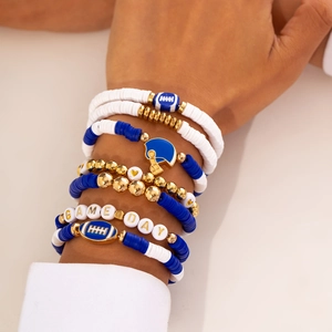 Detail of stacked Game Day beaded bracelets with football helmet charm in blue and gold