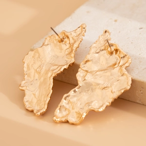 Detailed view of gold irregular teardrop earrings on a minimalist stone display stand