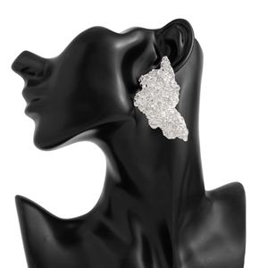 Detail of silver drop earrings with irregular hammered texture on a black display model