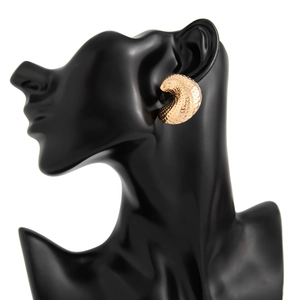 Detail showing gold irregular droplet earrings with textured honeycomb pattern on model