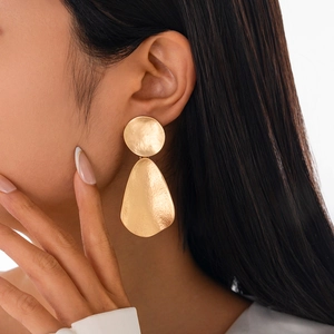 Golden irregular geometric water drop earrings with hammered texture on a model