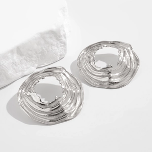 Dettaglio macro di orecchini in metallo liquido argento con texture lavica irregolare