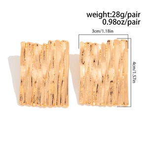 Dettaglio di orecchini rettangolari dorati con texture verticale e misure precise