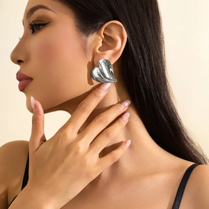 Primo piano della modella con orecchino a cuore in metallo liquido finitura argento