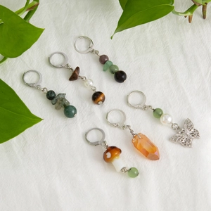 Set of crystal mushroom and butterfly dangle earrings on a white textured background