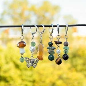 Macro detail of six handmade bohemian mushroom and butterfly charms with natural stones