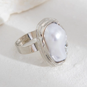 Vue macro de la bague argentée avec perle baroque et texture de métal froissé unique