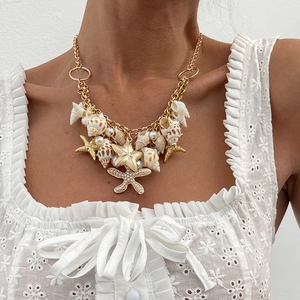 Close-up of golden starfish and seashell pendant belt with pearls on lace top