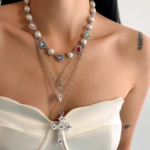 Detailopname van gelaagde kruisketting met kleurrijke hartstenen en parels op model
